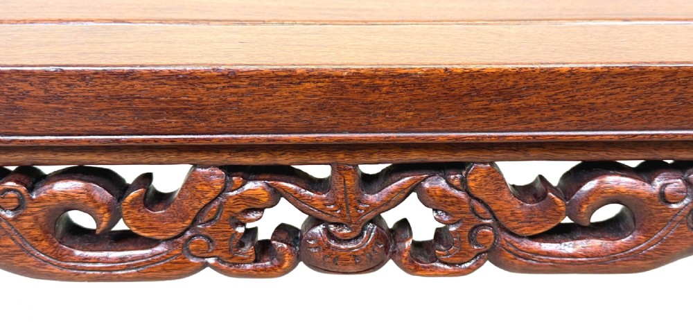 A low dark hardwood coffee table featuring an openwork carved apron and inward-curving scroll legs. View III