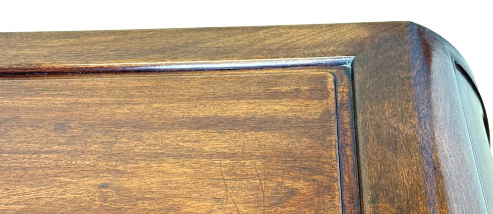 A low dark hardwood coffee table featuring an openwork carved apron and inward-curving scroll legs. View V