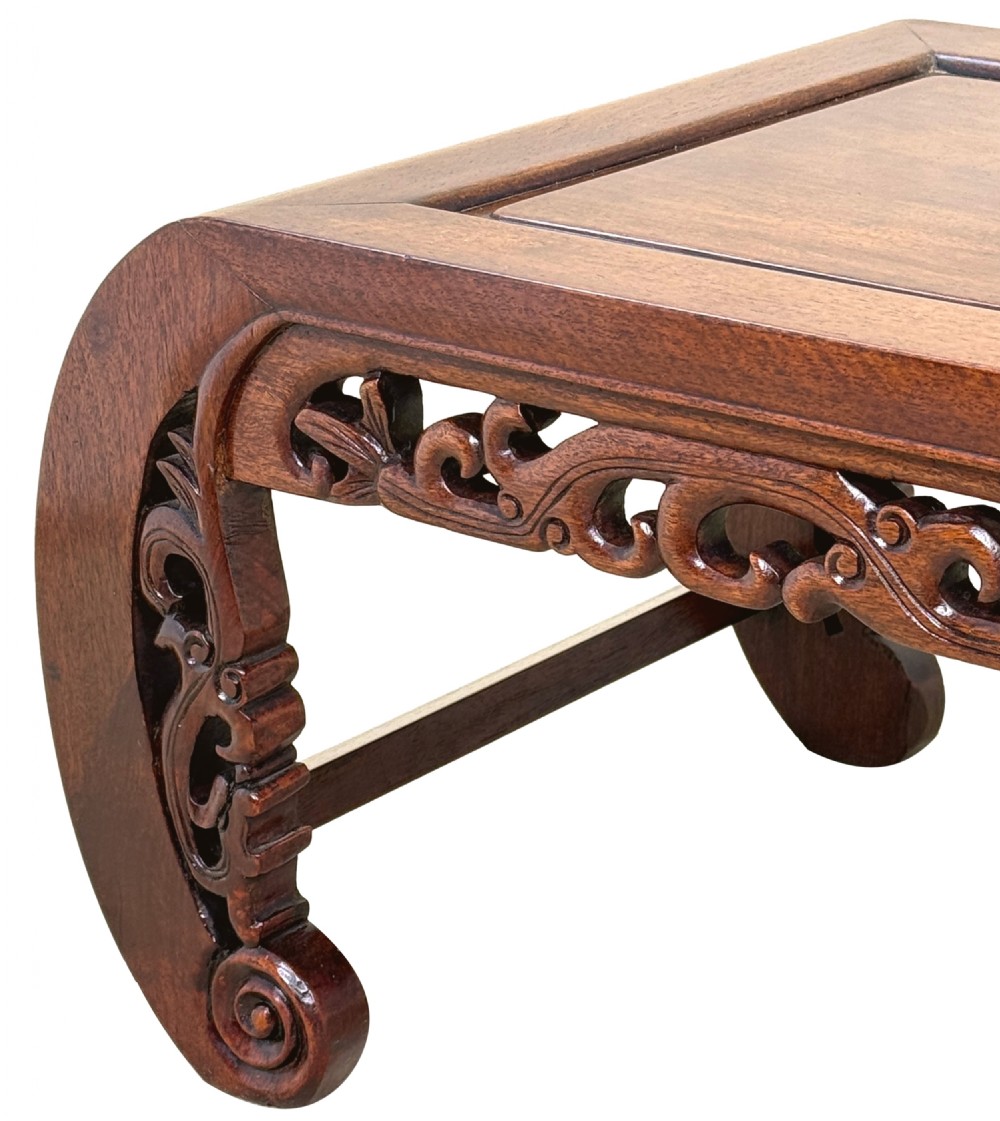 A low dark hardwood coffee table featuring an openwork carved apron and inward-curving scroll legs. View IX
