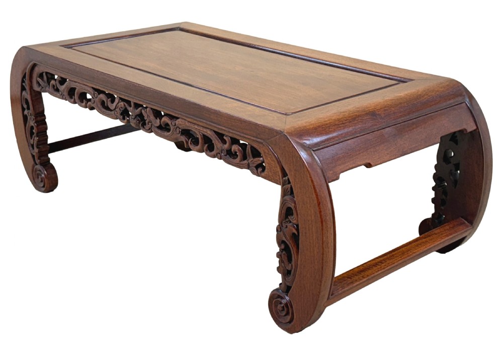 A low dark hardwood coffee table featuring an openwork carved apron and inward-curving scroll legs. View X