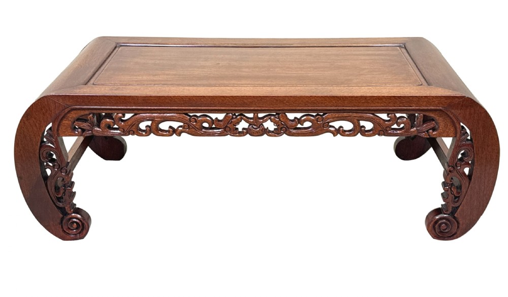 A low dark hardwood coffee table featuring an openwork carved apron and inward-curving scroll legs. View XII