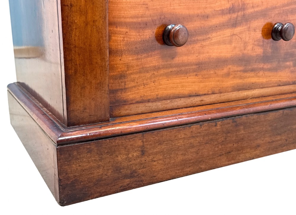 A tall Regency mahogany Wellington chest featuring seven stacked drawers with turned wooden handles, carved acanthus details, and a plinth base. View X