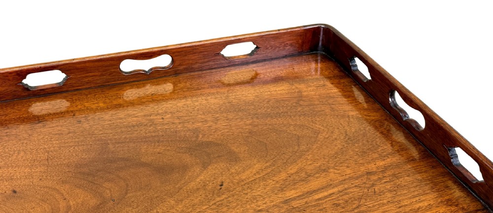 An 18th-century Georgian mahogany bedside table featuring a pierced tray top gallery with cut-out handles, double cupboard doors with a central brass pull, and square tapered legs. View IV