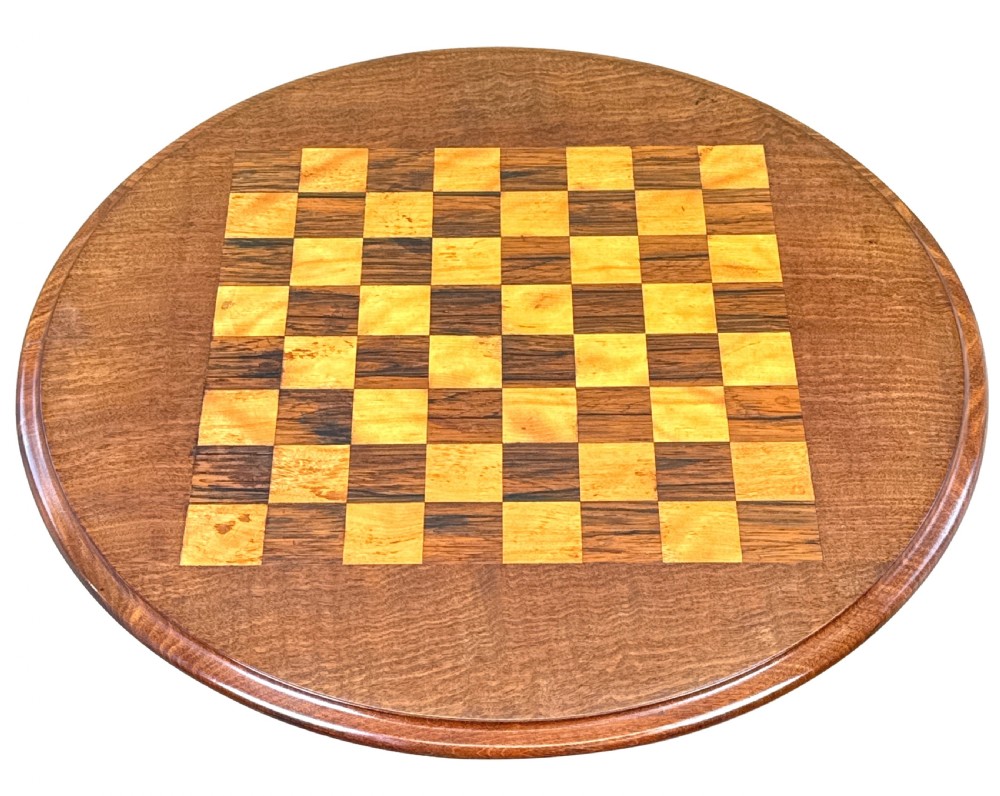 A mid-19th century mahogany lamp table featuring an inlaid square chessboard on a round top, supported by a faceted pedestal and a tri-form base with carved feet. View IV