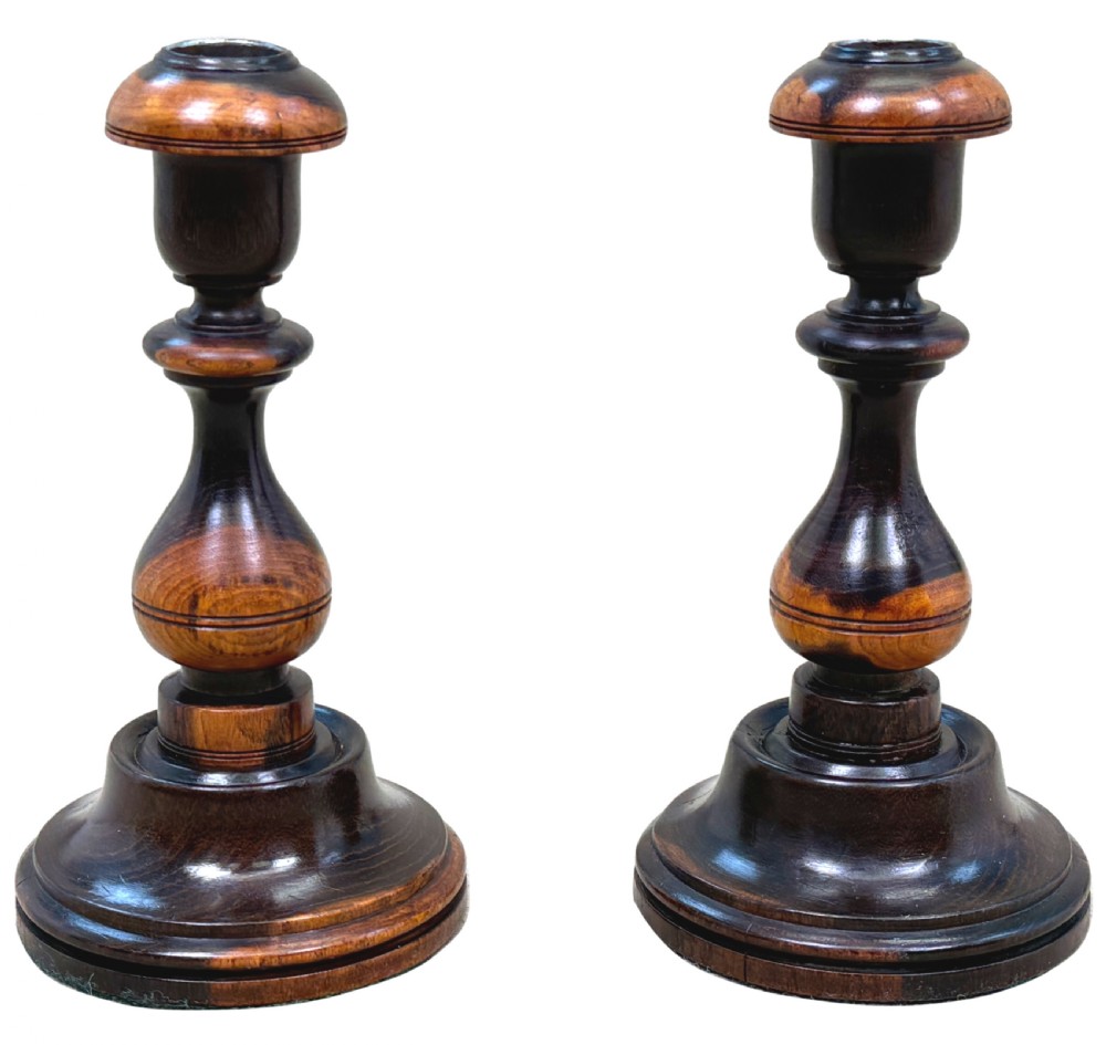 A pair of 19th-century turned lignum vitae wooden candlesticks featuring baluster-form stems, stepped circular bases, and contrasting dark and light graining. View IX