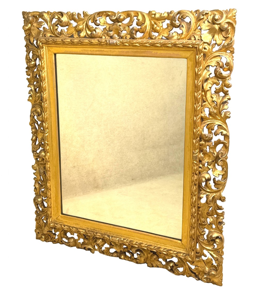 An early nineteenth-century rectangular Florentine wall mirror featuring an intricately carved foliage giltwood frame surrounding a rectangular glass plate. View II
