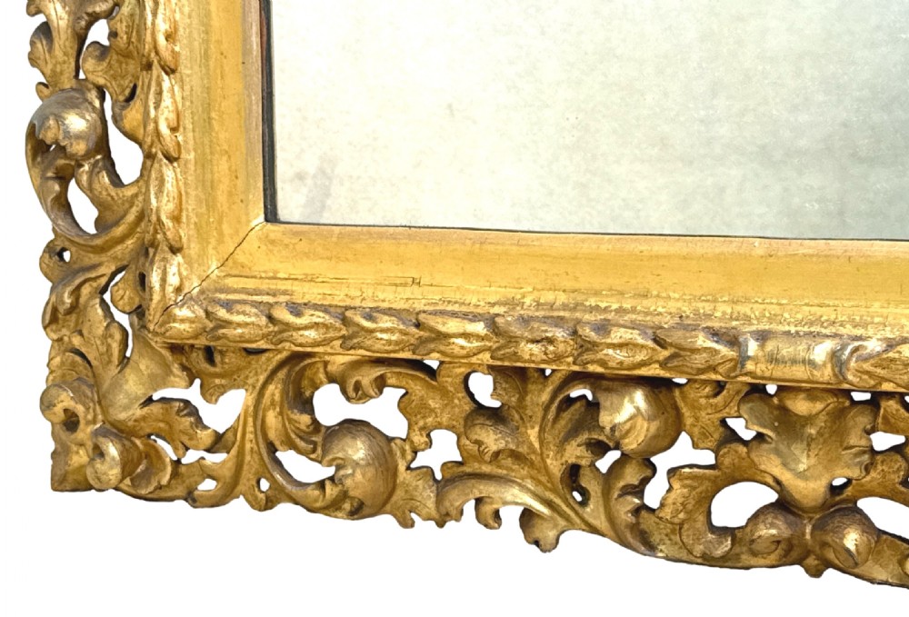 An early nineteenth-century rectangular Florentine wall mirror featuring an intricately carved foliage giltwood frame surrounding a rectangular glass plate. View IV
