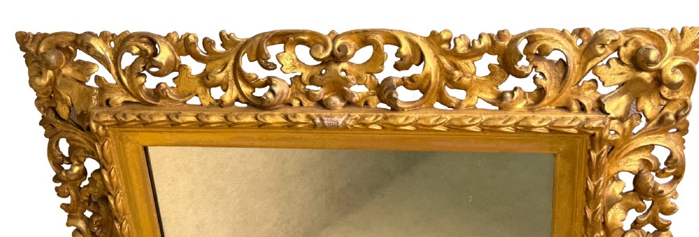 An early nineteenth-century rectangular Florentine wall mirror featuring an intricately carved foliage giltwood frame surrounding a rectangular glass plate. View V