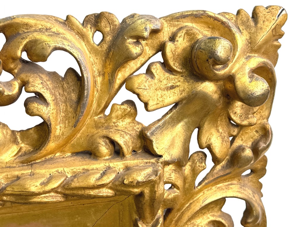 An early nineteenth-century rectangular Florentine wall mirror featuring an intricately carved foliage giltwood frame surrounding a rectangular glass plate. View VI