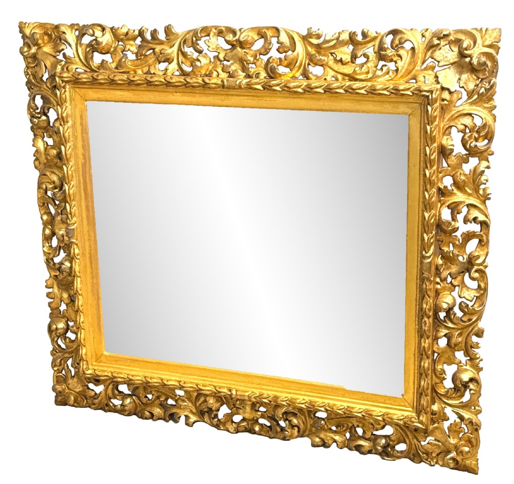 An early nineteenth-century rectangular Florentine wall mirror featuring an intricately carved foliage giltwood frame surrounding a rectangular glass plate. View IX