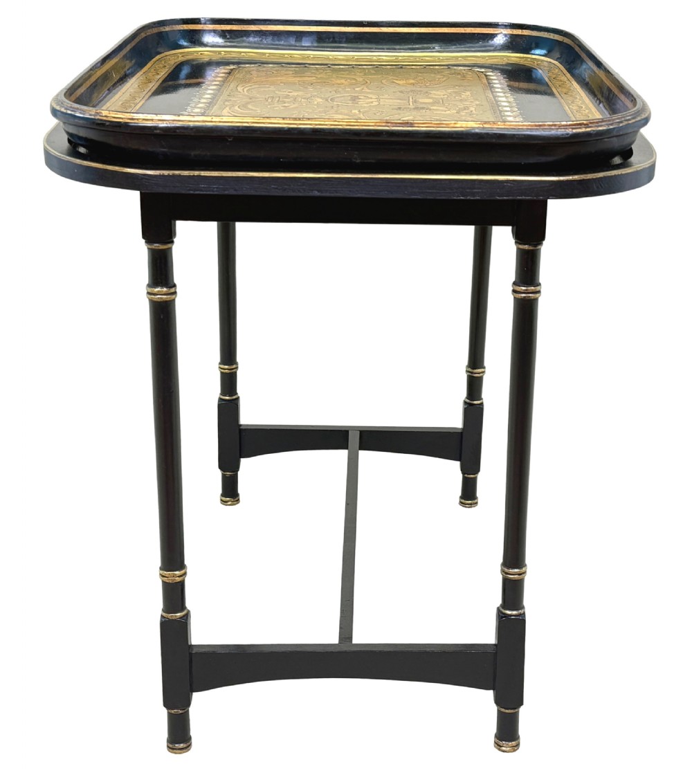 A 19th-century black papier-mache tray featuring gilded rim decoration, resting on a black turned wooden stand with gold accent rings. View VI