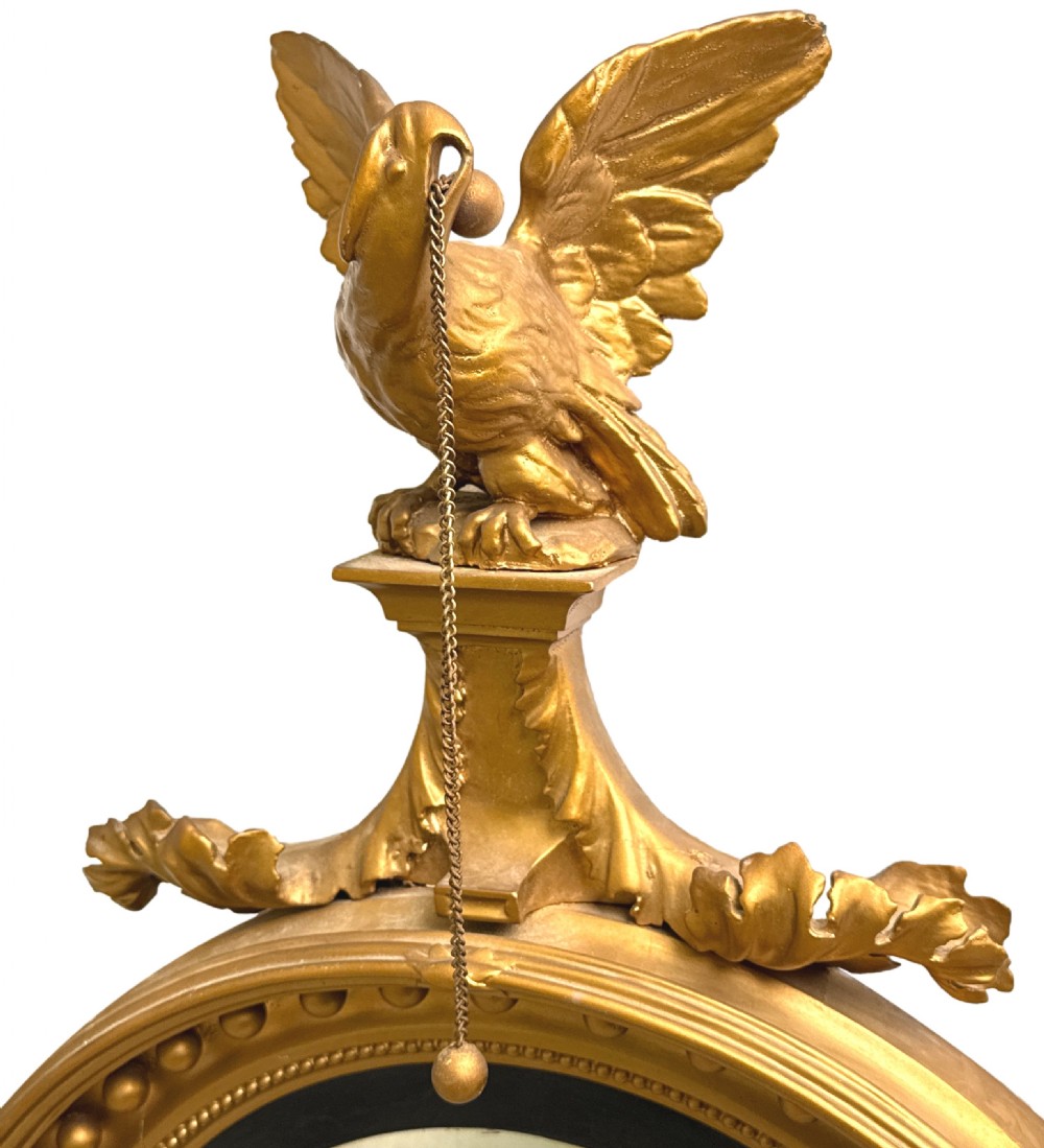 A circular mid-19th-century convex mirror featuring a gilded frame with sphere details, an ebonised inner slip, and a carved eagle cresting at the top. View V