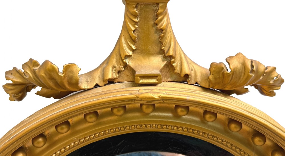 A circular mid-19th-century convex mirror featuring a gilded frame with sphere details, an ebonised inner slip, and a carved eagle cresting at the top. View VI