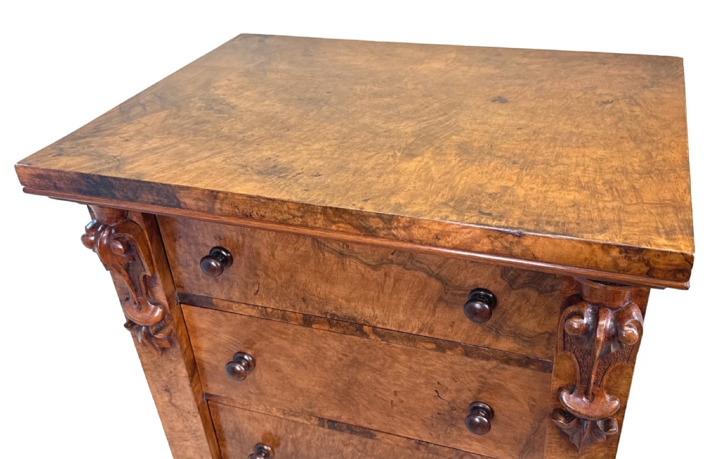 A mid 19th-century burr walnut Wellington chest featuring seven drawers, carved corbels, turned wood handles, and a hinged side locking bar on a plinth base. View V