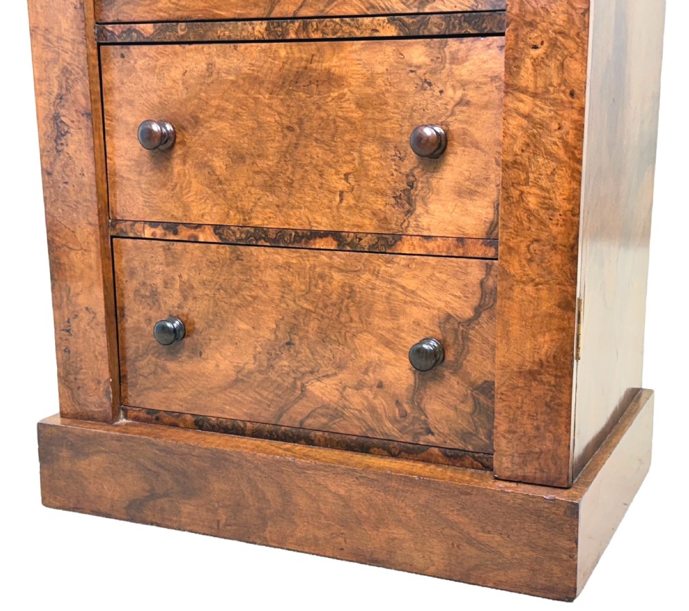 A mid 19th-century burr walnut Wellington chest featuring seven drawers, carved corbels, turned wood handles, and a hinged side locking bar on a plinth base. View VII