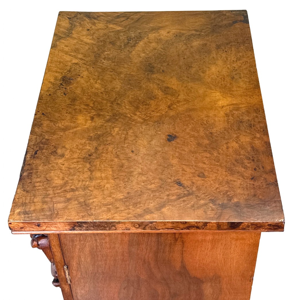 A mid 19th-century burr walnut Wellington chest featuring seven drawers, carved corbels, turned wood handles, and a hinged side locking bar on a plinth base. View X