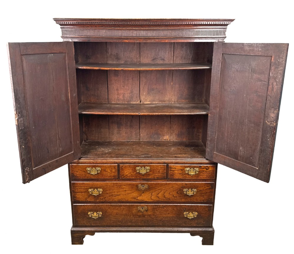 An 18th-century Georgian dark oak press cupboard featuring an upper double-door cabinet with fielded panels over a chest of drawers with brass handles. View II