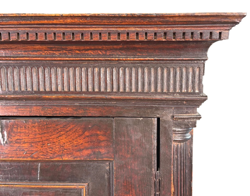 An 18th-century Georgian dark oak press cupboard featuring an upper double-door cabinet with fielded panels over a chest of drawers with brass handles. View V
