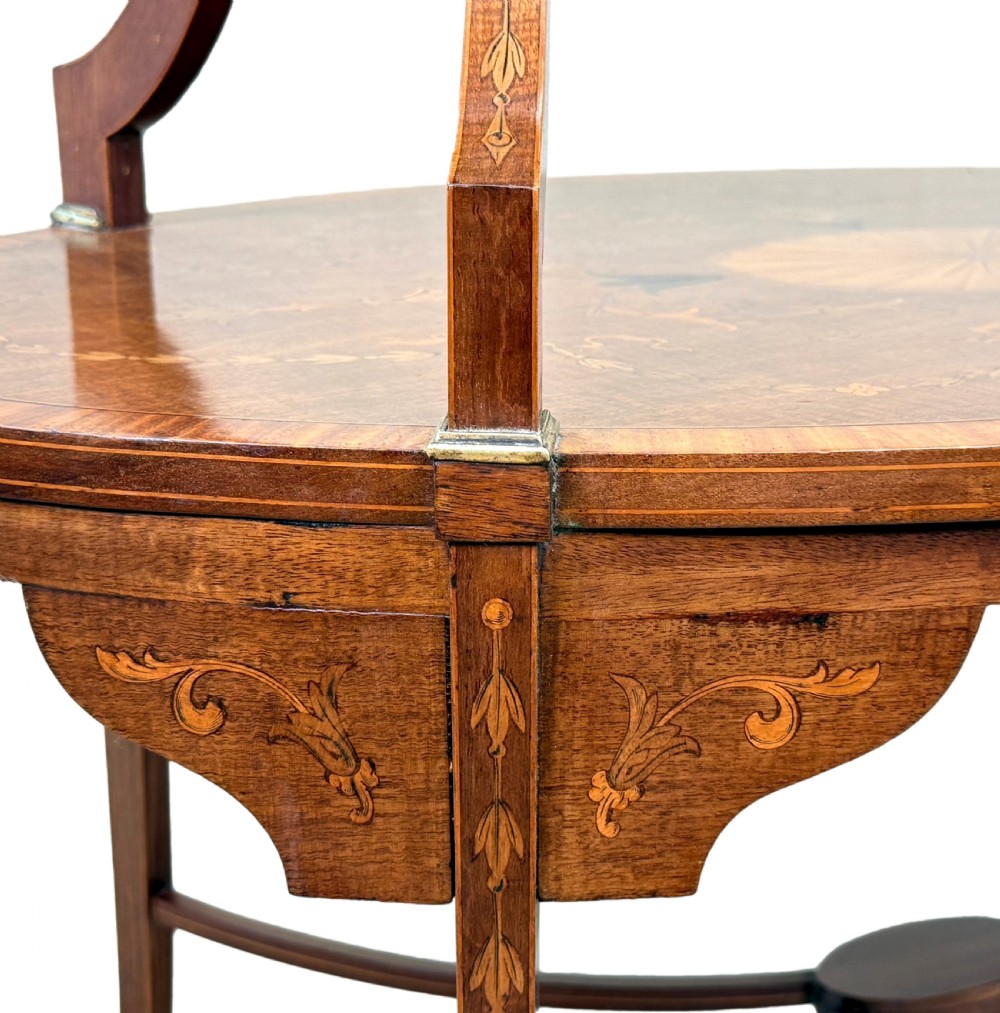 A 19th-century oval two-tier mahogany table featuring satinwood marquetry inlay, a scalloped top tier gallery with brass handles, and curved legs. View V