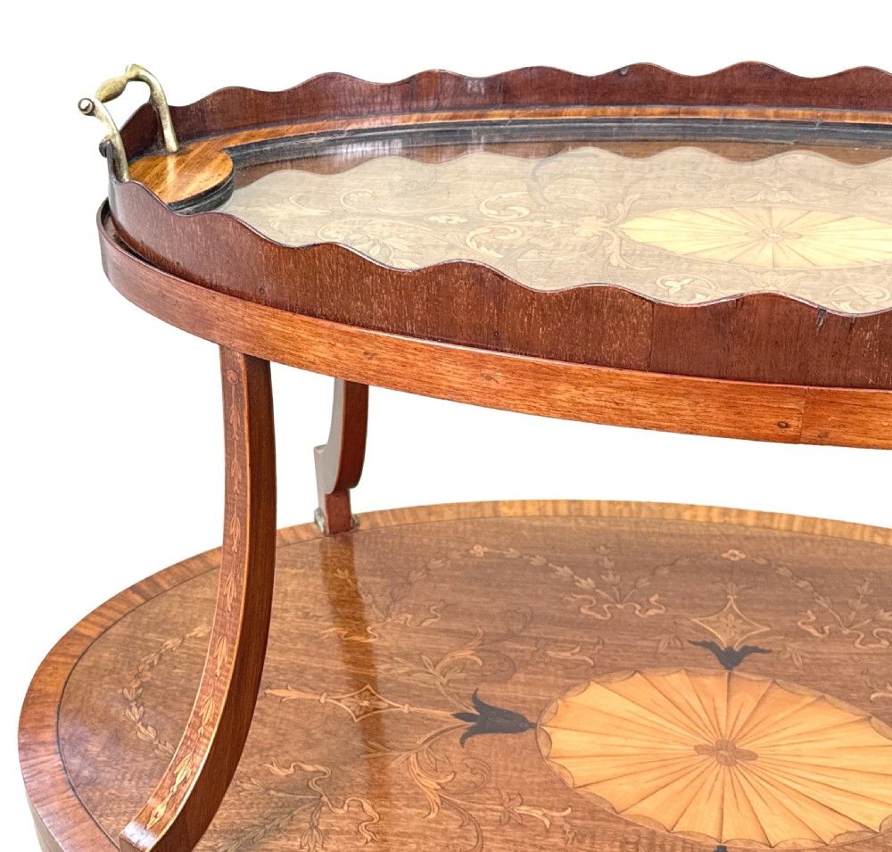 A 19th-century oval two-tier mahogany table featuring satinwood marquetry inlay, a scalloped top tier gallery with brass handles, and curved legs. View XI