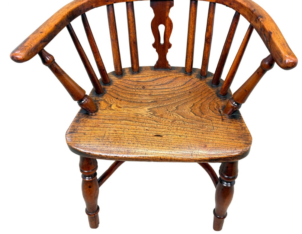 A 19th-century childs Windsor armchair crafted from yew wood, featuring a hoop back with a pierced fretwork splat, turned legs, and a curved stretcher. View V