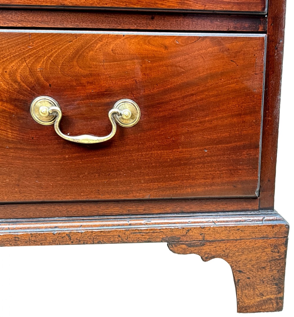 A George III mahogany chest of drawers featuring two short drawers over three long graduated drawers with brass swan-neck handles and bracket feet. View II