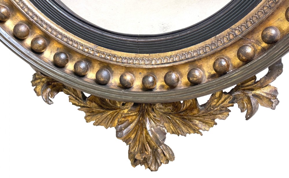 A circular Regency giltwood convex mirror with a carved eagle cresting, ball ornamentation along the frame, and acanthus leaf apron. View IV