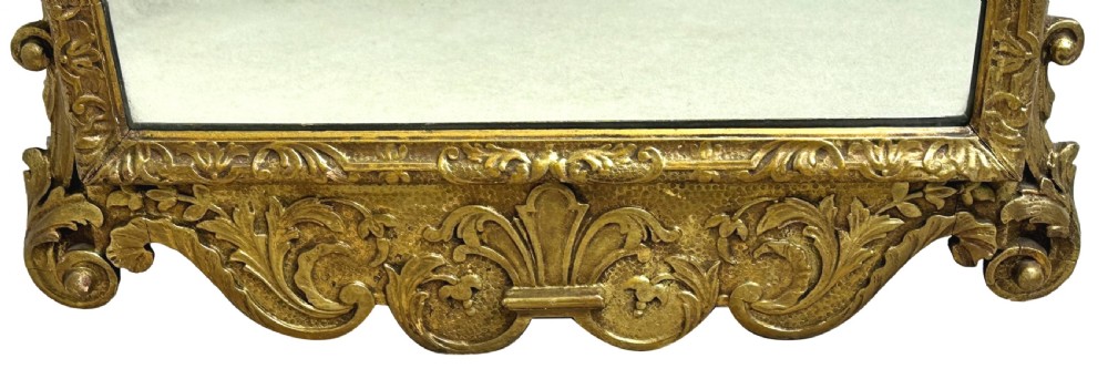 A tall late nineteenth-century carved giltwood wall mirror featuring elaborate cresting with carved sculpted heads, foliage motifs, and scrollwork. View V