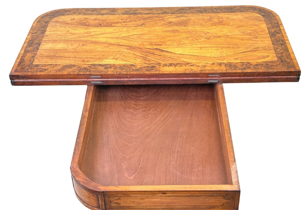 A nineteenth-century Regency kingwood card table with an inlaid fold-over top, ebonised turned pillar supports, and splayed legs with gilded lion paw feet. View V