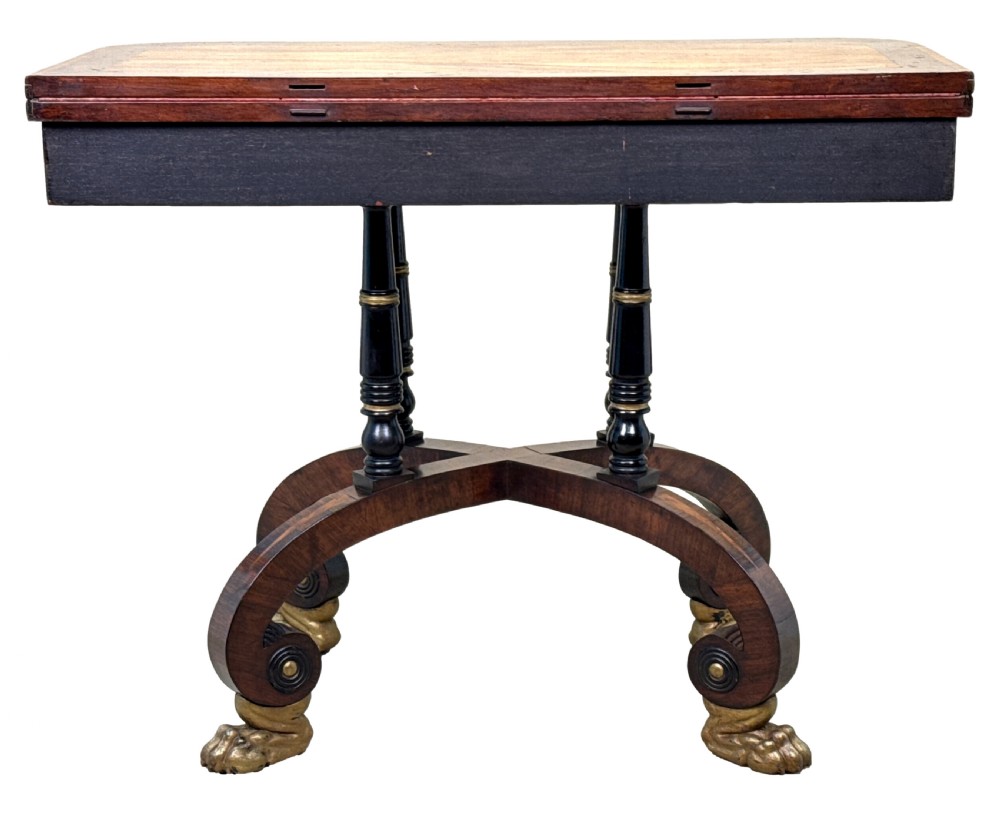 A nineteenth-century Regency kingwood card table with an inlaid fold-over top, ebonised turned pillar supports, and splayed legs with gilded lion paw feet. View XIV