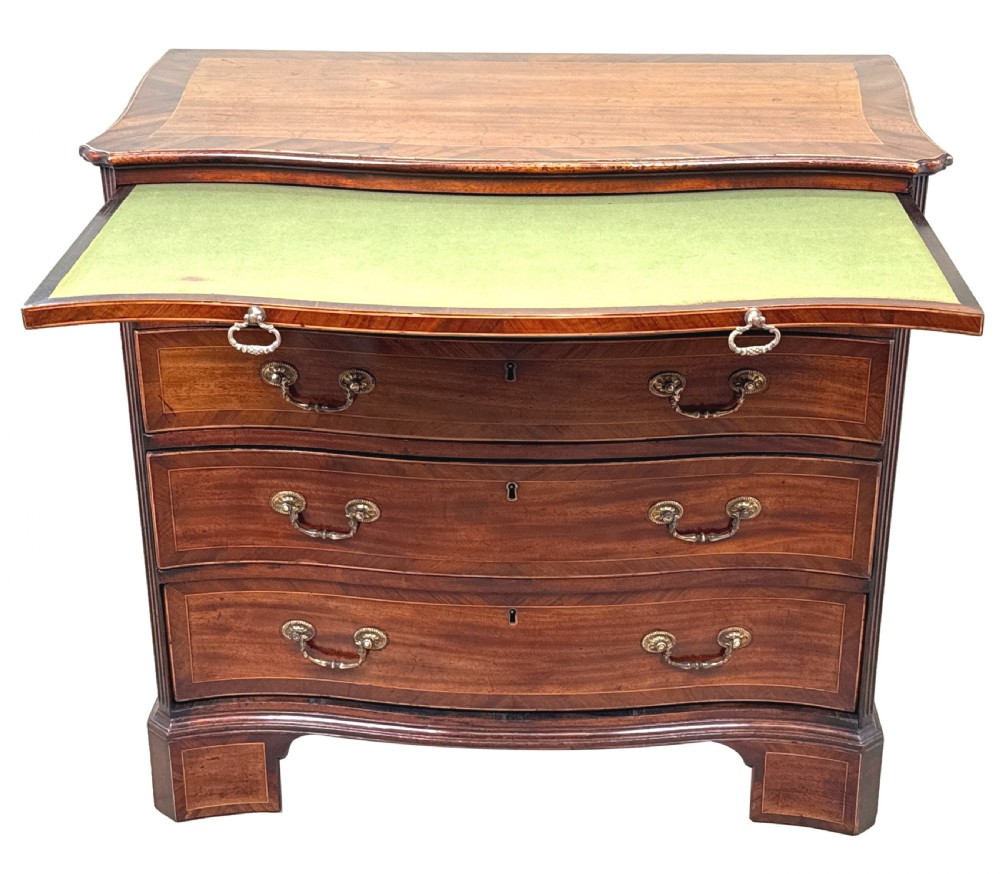 A George III mahogany serpentine chest of drawers featuring four graduated drawers with brass handles and inlaid stringing, supported on bracket feet. View V