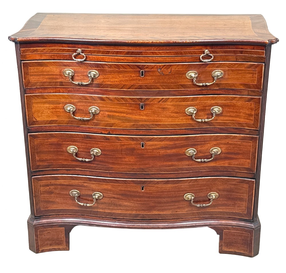 A George III mahogany serpentine chest of drawers featuring four graduated drawers with brass handles and inlaid stringing, supported on bracket feet. View XIII