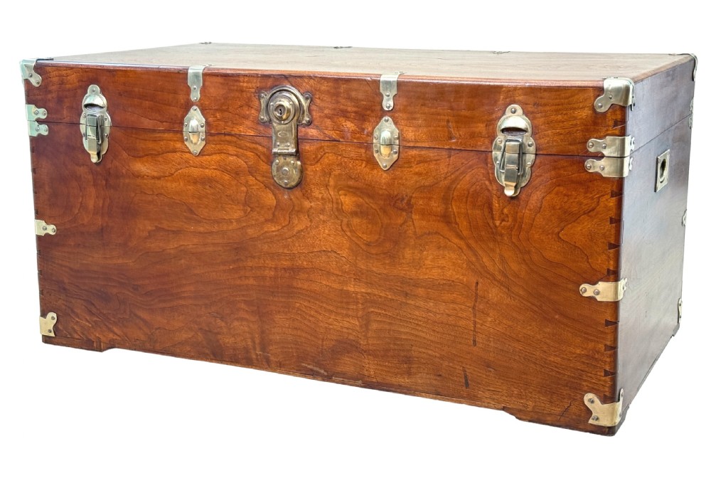 A large nineteenth-century camphor wood campaign trunk featuring brass corner mounts, heavy latches, and exposed dovetail joints.