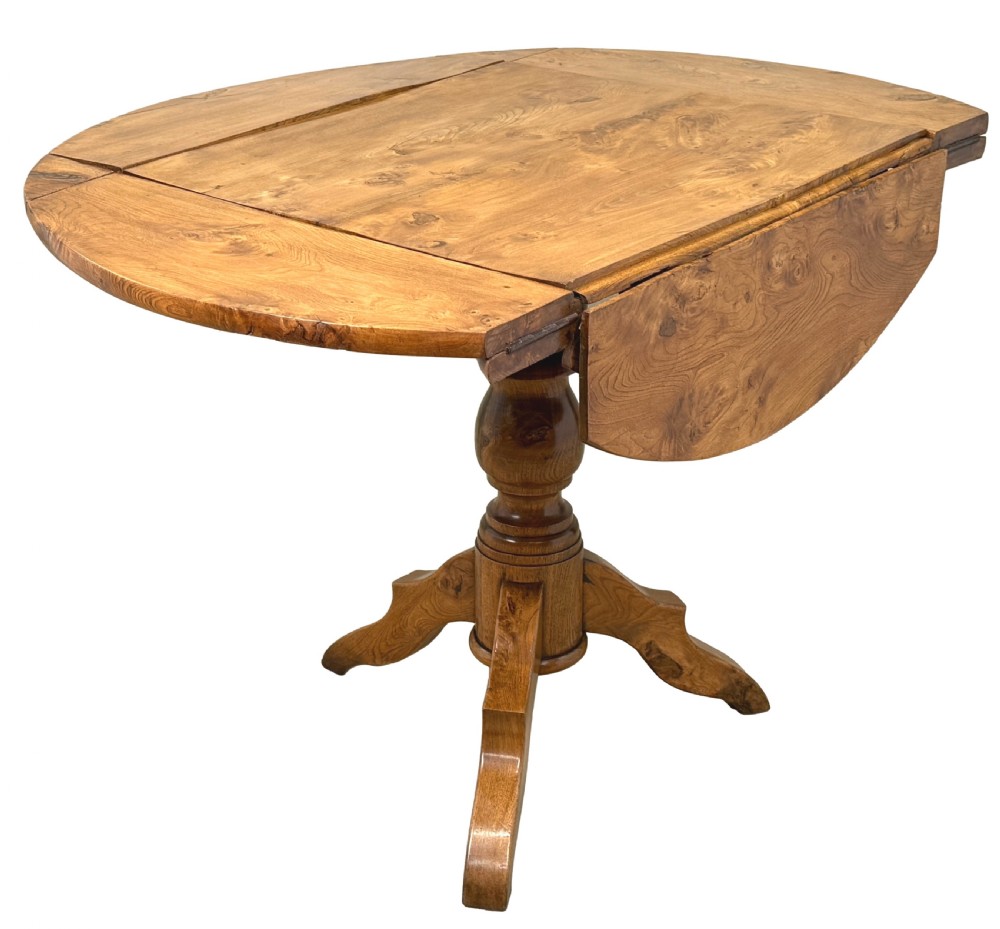 A nineteenth-century French Provincial elm centre table featuring a round top with two drop leaves, a turned central pedestal, and a three-legged tripod base. View VII