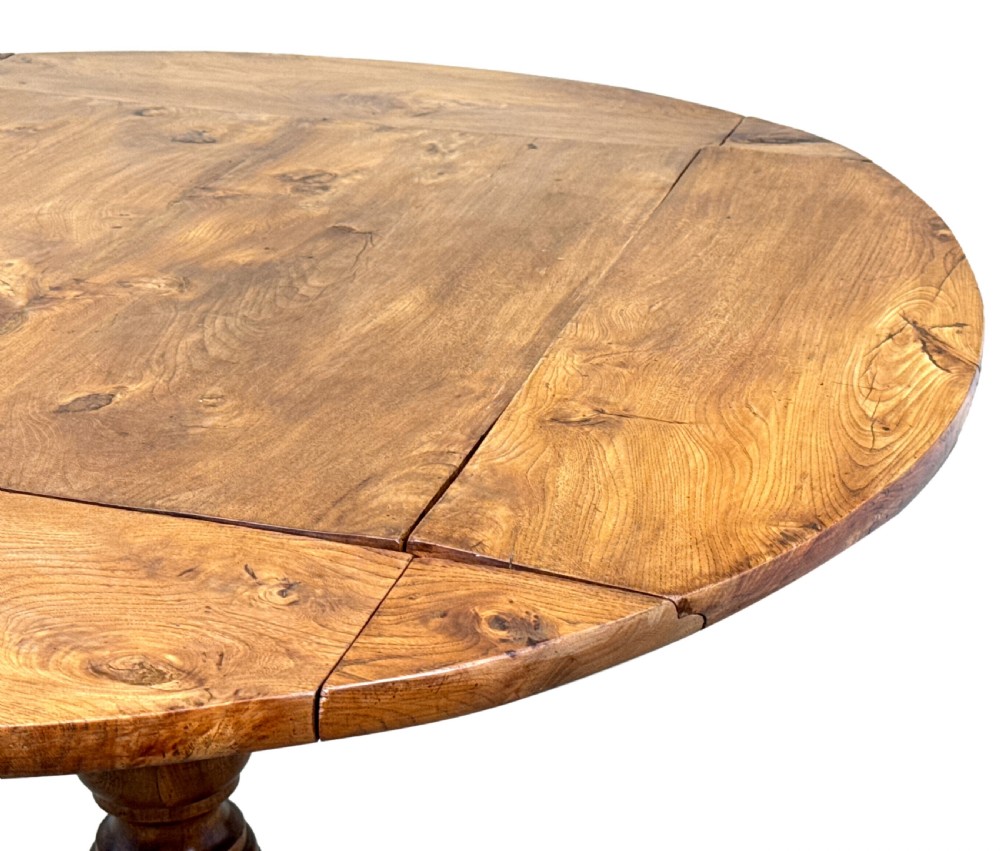 A nineteenth-century French Provincial elm centre table featuring a round top with two drop leaves, a turned central pedestal, and a three-legged tripod base. View VIII