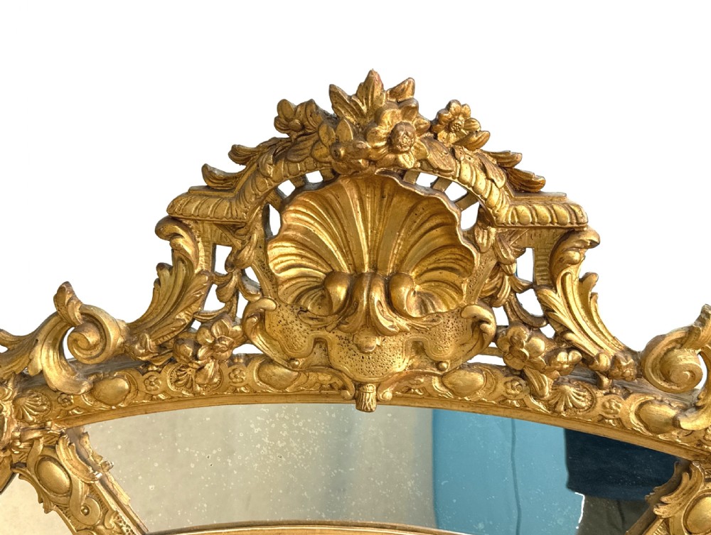 A large French 19th-century gilt overmantel mirror featuring an arched frame with marginal mirror plates, an ornate shell cresting, and carved foliage details. View II