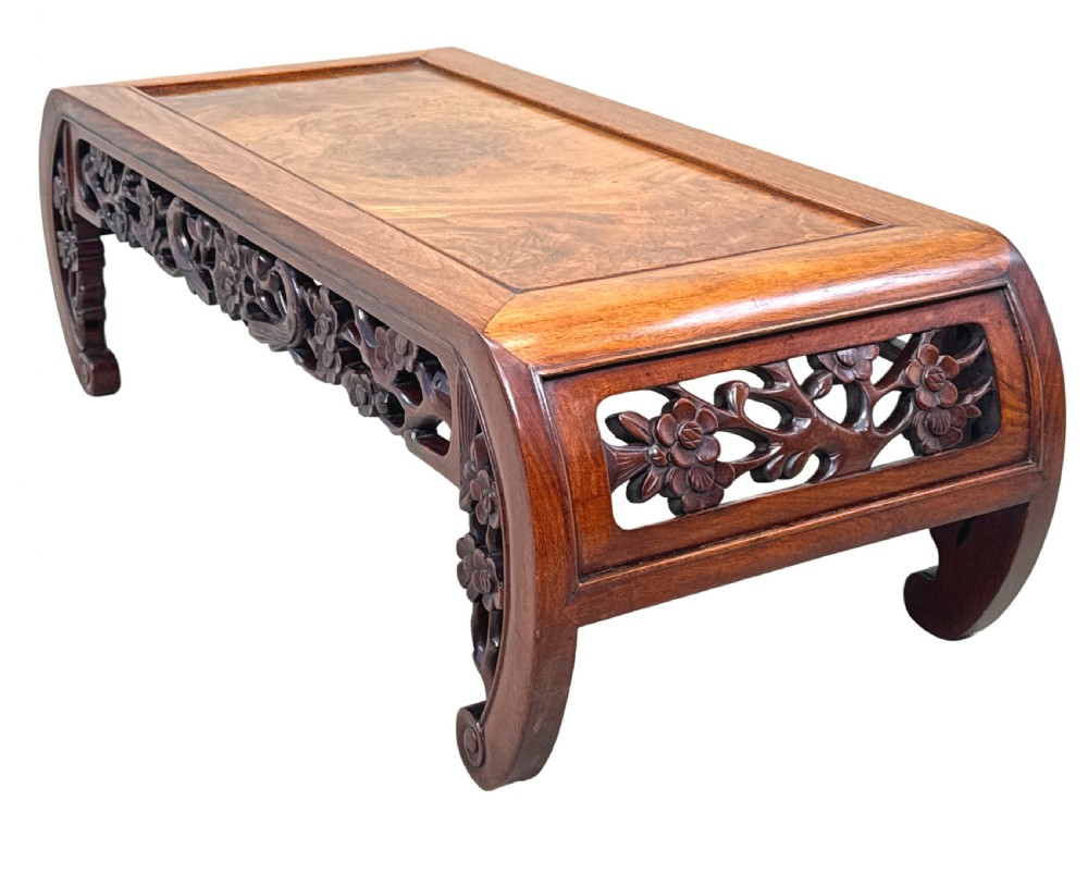 A low-profile 19th-century Oriental hardwood coffee table featuring an intricately carved floral apron and inwardly curved scroll legs. View II