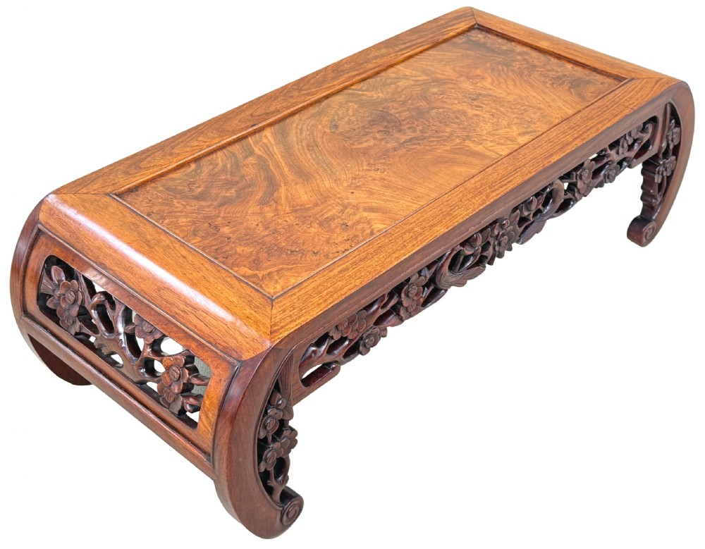 A low-profile 19th-century Oriental hardwood coffee table featuring an intricately carved floral apron and inwardly curved scroll legs. View VII