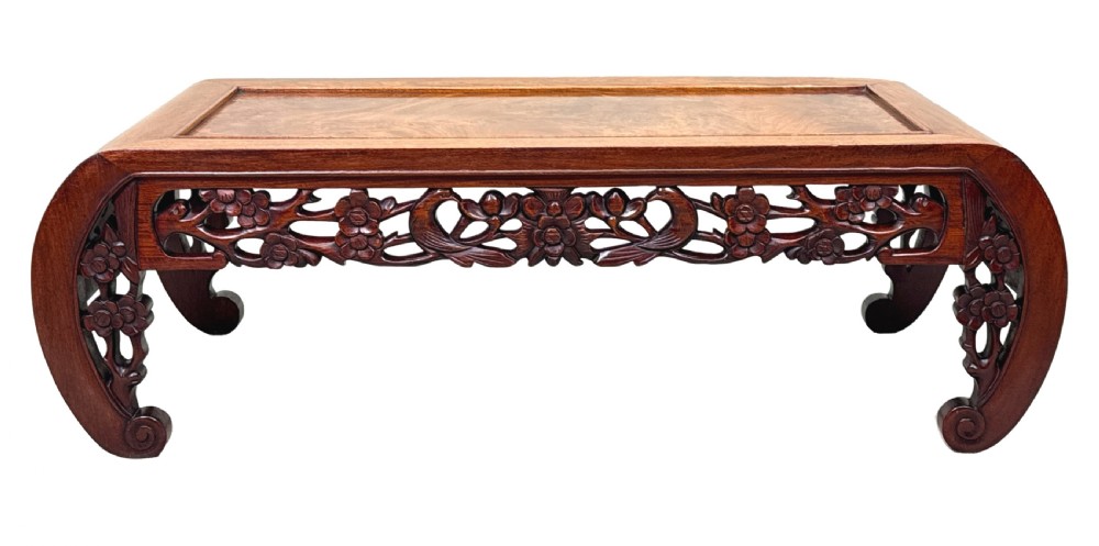 A low-profile 19th-century Oriental hardwood coffee table featuring an intricately carved floral apron and inwardly curved scroll legs. View IX