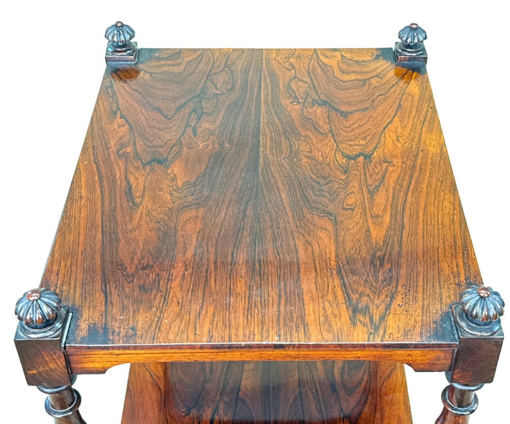 A three-tier Regency rosewood whatnot stand featuring slender turned column supports, decorative top corner finials, and brass castors. View VI
