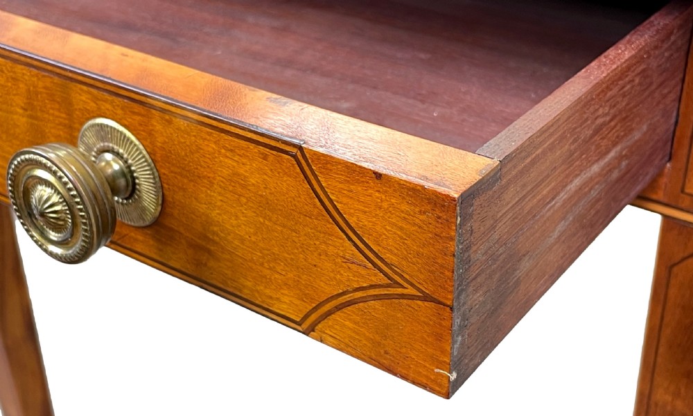 A late 18th-century Georgian satinwood Pembroke table featuring two hinged drop leaves, dark wood crossbanding, a drawer with brass knobs, and tapered square legs with castors. View X