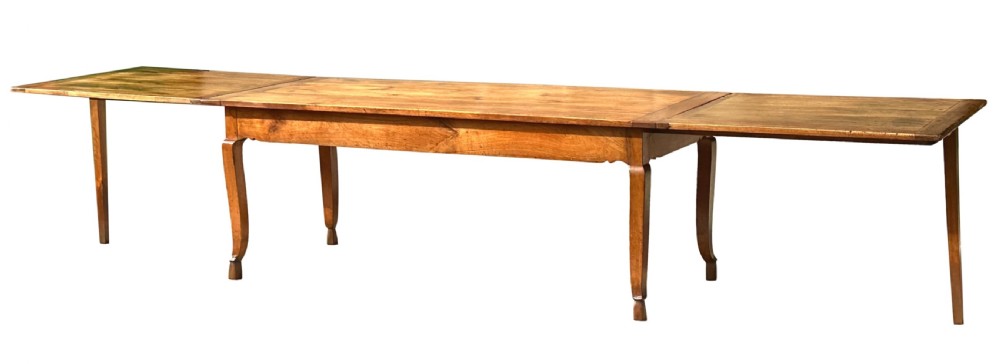 An early 19th-century warm brown extending farmhouse dining table with two end pull-out extensions supported by additional legs.
