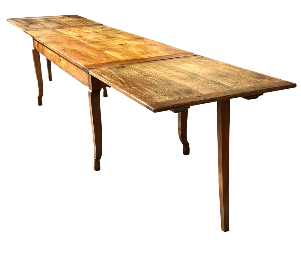 An early 19th-century warm brown extending farmhouse dining table with two end pull-out extensions supported by additional legs. View II