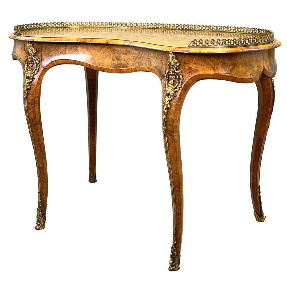 A 19th-century kidney-shaped burr walnut table featuring marquetry inlay, cabriole legs, and brass ormolu mounts with a pierced gallery edge.