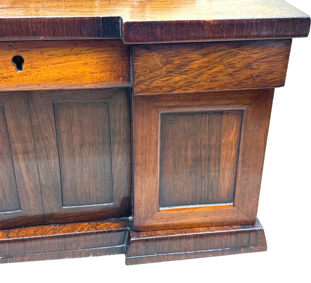 A dark rosewood tea caddy crafted in the shape of a miniature Regency breakfront sideboard with a carved cresting backboard. View V