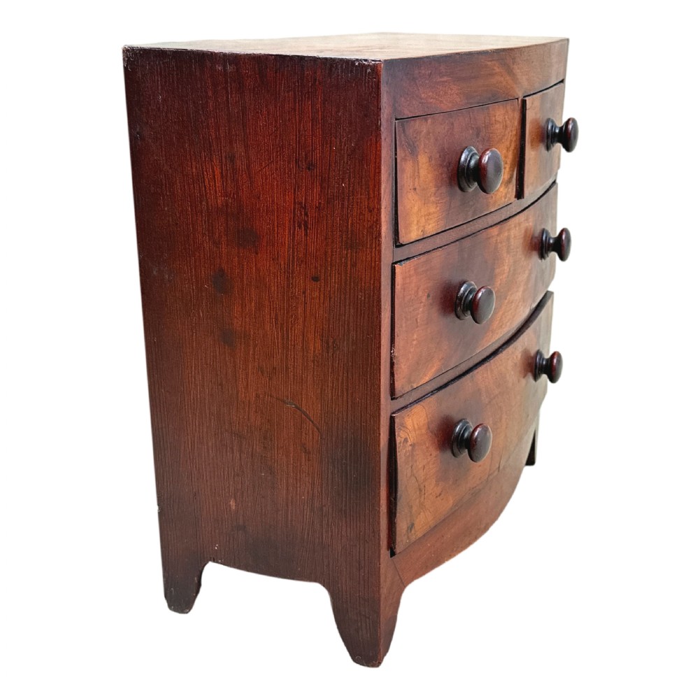 A Victorian miniature mahogany bowfront chest featuring two short over two long drawers with turned wooden knobs and bracket feet. View III
