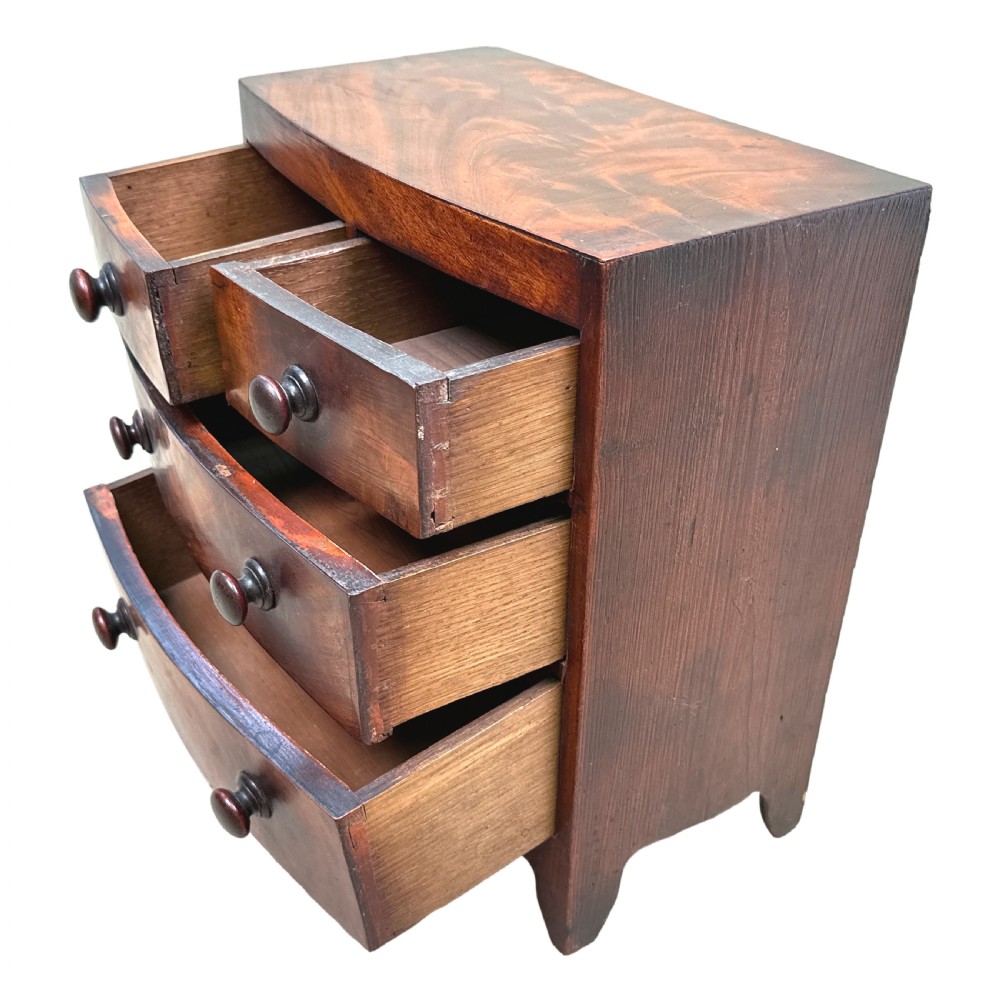 A Victorian miniature mahogany bowfront chest featuring two short over two long drawers with turned wooden knobs and bracket feet. View IV