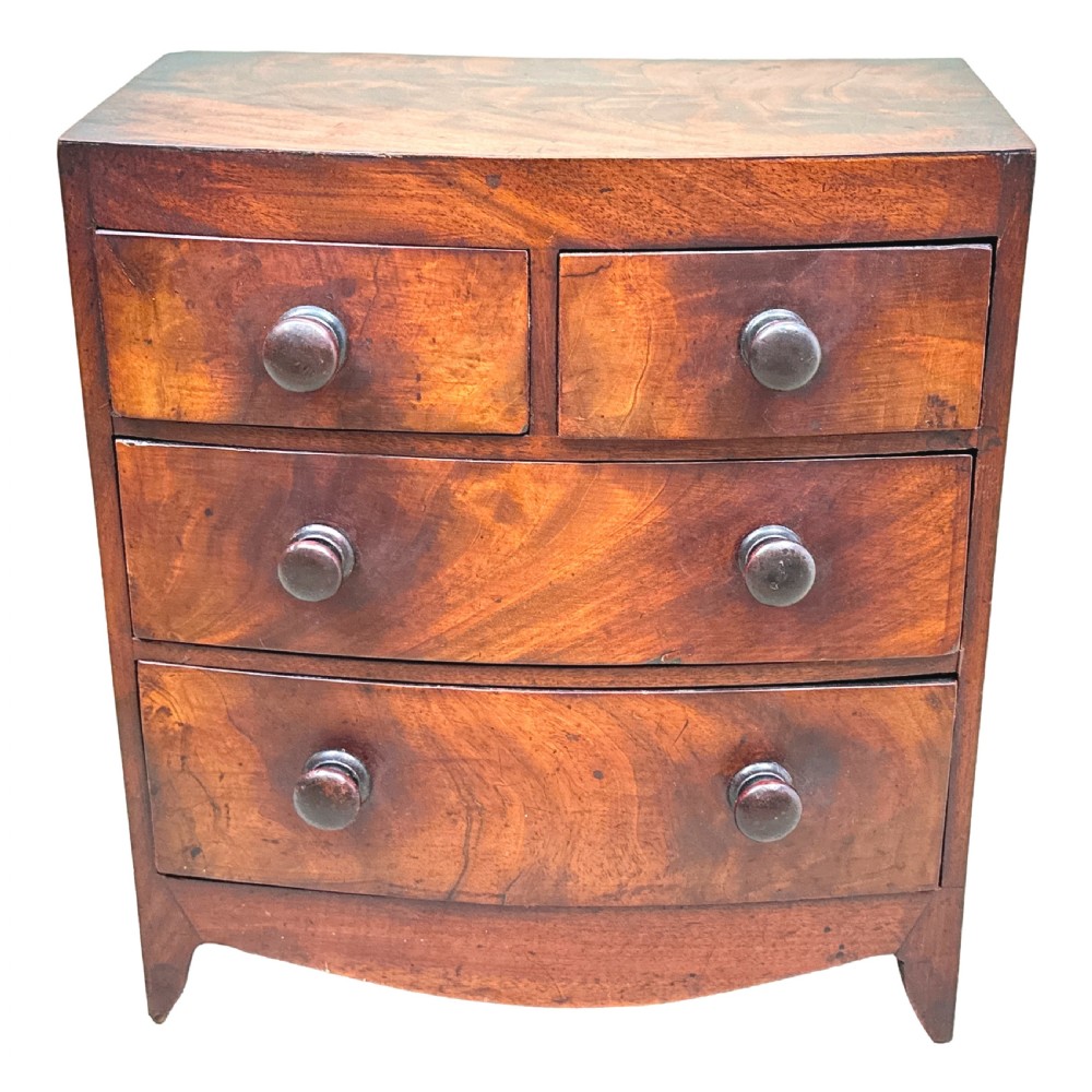 A Victorian miniature mahogany bowfront chest featuring two short over two long drawers with turned wooden knobs and bracket feet. View X