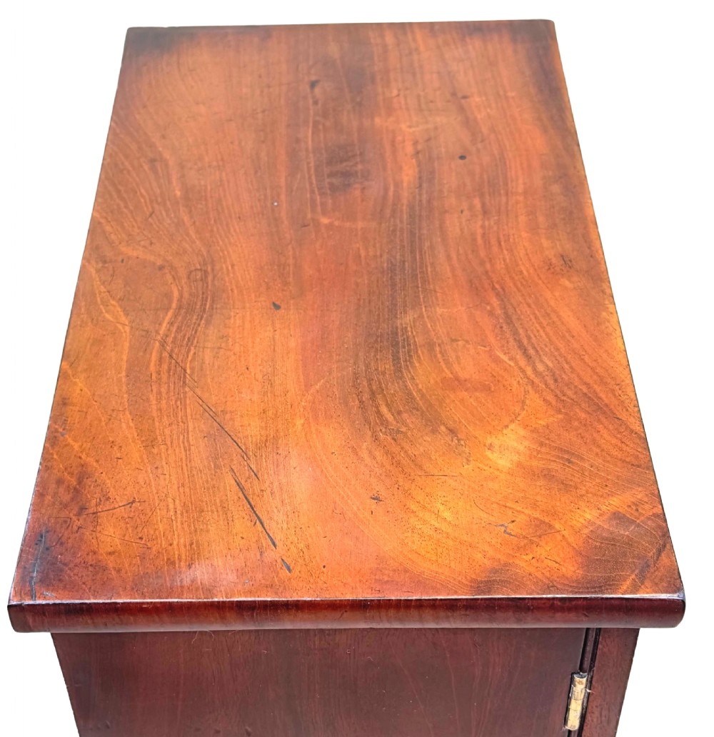 A Regency flame mahogany twin-door miniature table cabinet with turned feet, bead moulding, and brass escutcheons. View III
