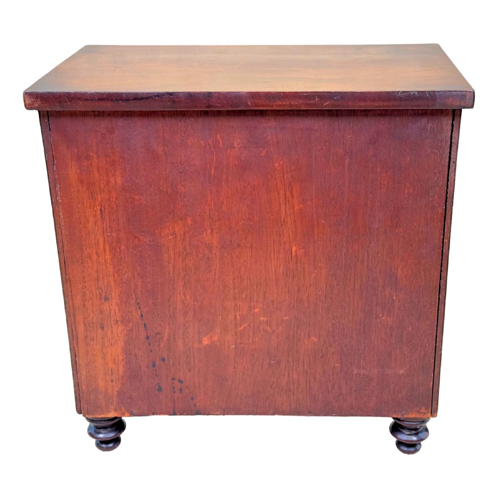 A Regency flame mahogany twin-door miniature table cabinet with turned feet, bead moulding, and brass escutcheons. View IX